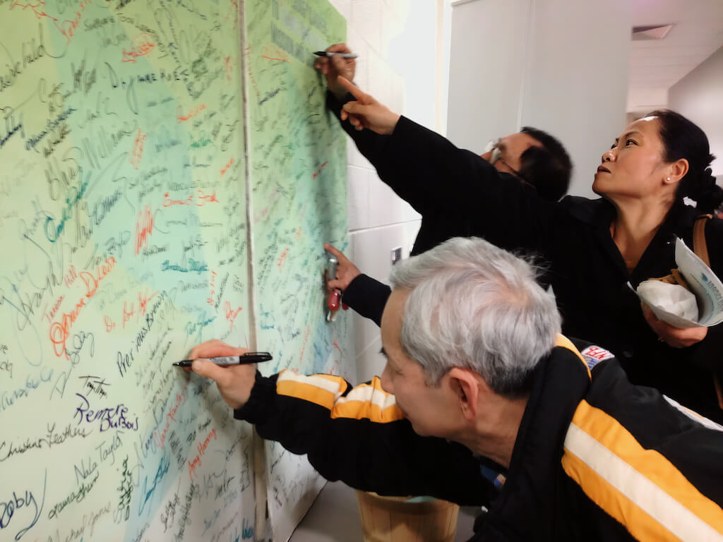 Community autographing a wall
